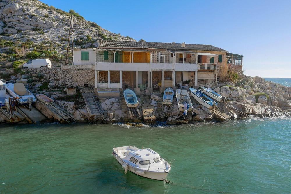 Petit port de Callelongue avec barques hissées sur les cales rocheuses et cabanons traditionnels à Marseille